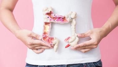 Woman holding plastic model of intestines showing off colorectal cancer