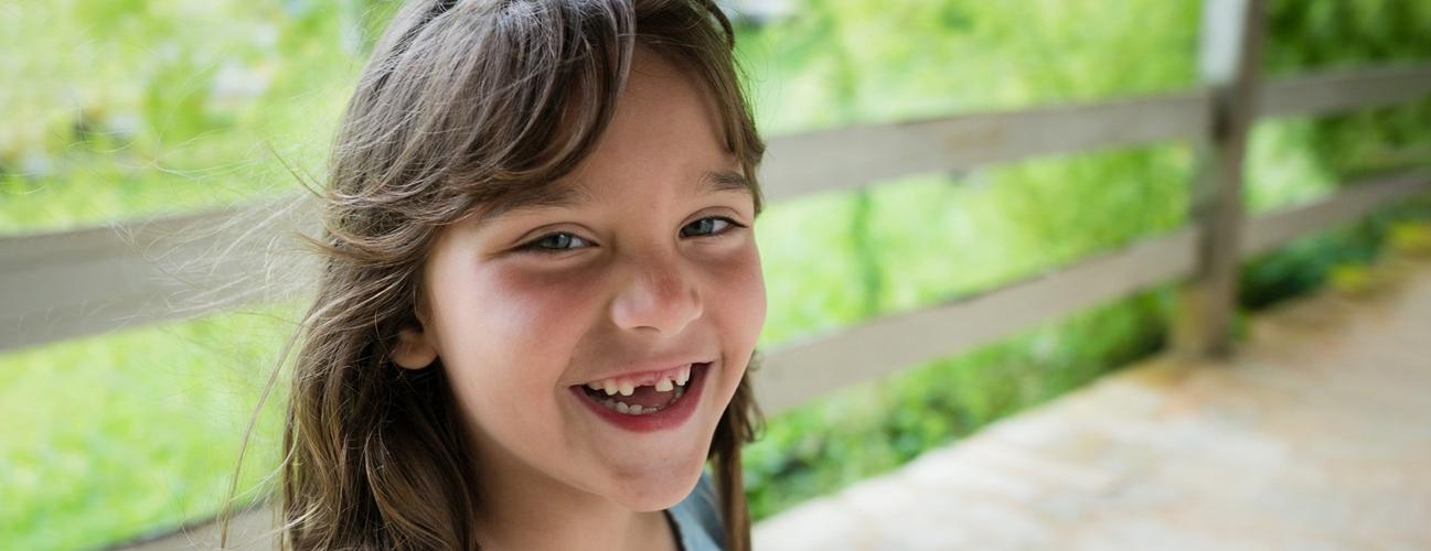 一个小女孩笑得很开心，露出她缺失的牙齿.