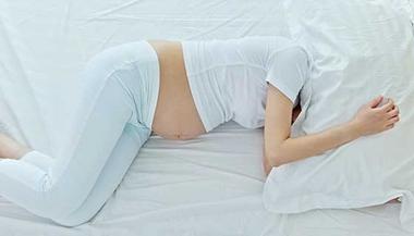 Pregnant woman hiding her head under a pillow