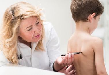 a pediatrician screens a boy for scoliosis