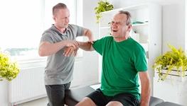 Physical therapist examining senior man's shoulder problem