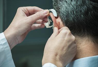 doctor placing hearing aid to a patient