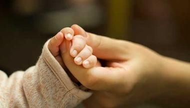 Baby holding mother's hand.