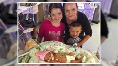 卡西，一个患有唐氏综合症的新生儿，与她的哥哥、妹妹和母亲合影.