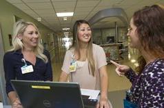 Three women around a laptop learning about the residency program at Johns Hopkins All Children's Hospital.