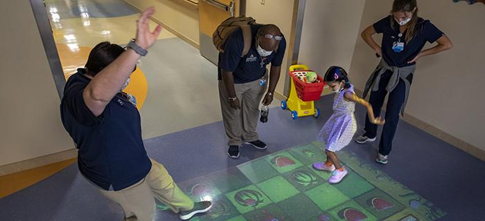 在约翰霍普金斯儿童医院的走廊里，一个小女孩正在和一名员工玩游戏.